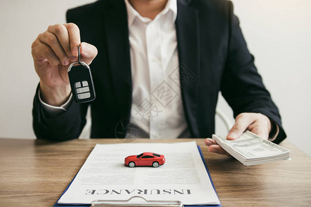 汽车销售人员通过向具有汽车保险概念的新车购买者图片