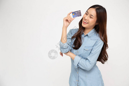 一位快乐的年轻女手持自动取款机借记卡或信用卡并用于在线购物图片