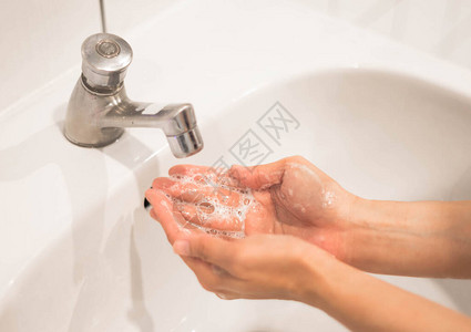 妇女用自来水和肥皂洗手图片