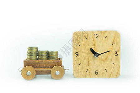 玩具火车和白色背景的木头手表上的金质硬币储备图片