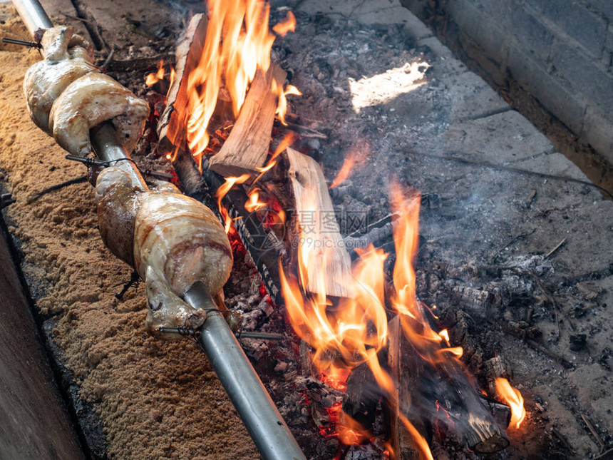 在明亮发光的山毛榉木炭上烤的鸡用香料刷在烤架图片
