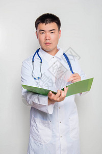 一位身穿白大褂脖子上挂着听诊器的医生正在阅读绿色文件夹中的测试一个图片