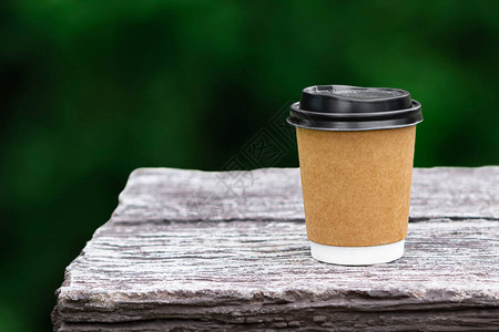 天然绿色模糊背景的石头桌上可使用咖啡纸杯模型背景图片
