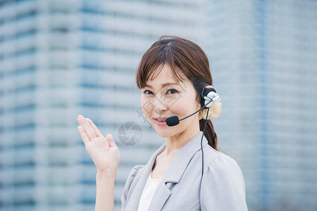 亚洲日语女经营者在商业区戴带麦克风的耳机图片素材