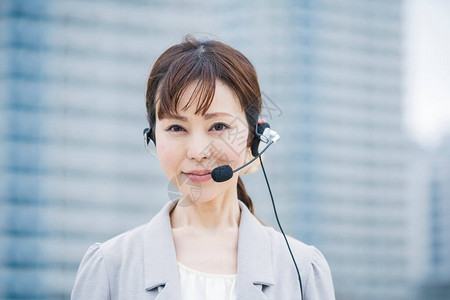 亚洲日语女经营者在商业区戴带麦克风的耳机图片素材
