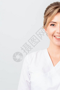 半脸美丽的医生或实习生或穿着白色长袍的美容师的肖像站在镜头前微笑图片