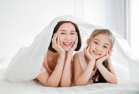 快乐的母亲和少女在床图片