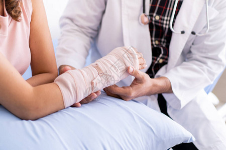 骨科专医生用夹板和绷带检查严重受伤的妇女手臂医生在医院与断臂女病人交谈在受伤的背景图片
