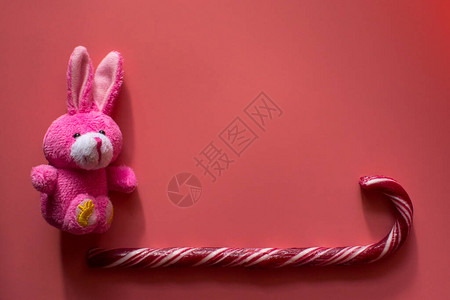 漂亮的玩具兔子和焦糖在黑暗的粉红背景作为贺会卡复制空间图片