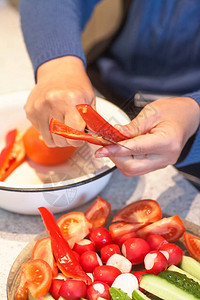 女人的手切黄瓜在新鲜蔬菜的后面图片