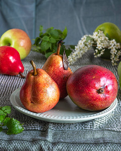 水果放在绿色桌布苹果梨子和芒果上图片