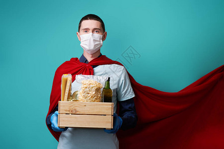 戴着外科口罩和超级英雄斗篷的志愿者拿着食物盒头孢爆发期间超级英雄主义图片