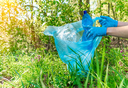 塑料垃圾对地球的全球污染志愿者通过收集废物清理森林和草图片