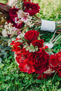 新娘美丽的红色婚礼花束躺在绿草地上户外婚礼婚礼当天婚礼装图片