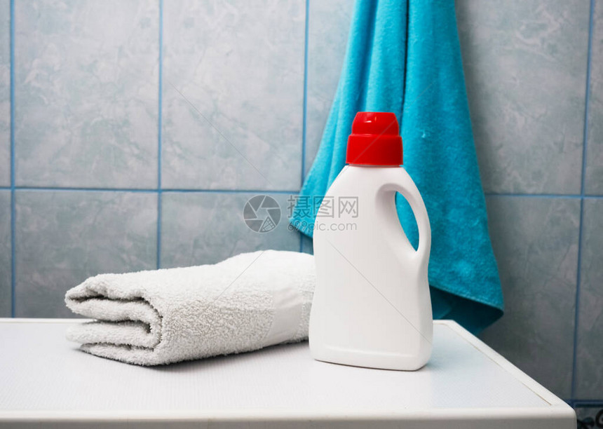 室内洗衣机上装了一瓶洗涤剂和干净毛巾图片