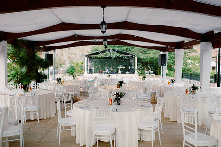 圆桌与白色桌布和白色Chiavary椅子在一个大白色帐篷下图片