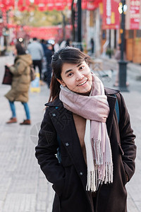 云南昆明市购物街上带毛衣和背包的年轻女旅行者图片