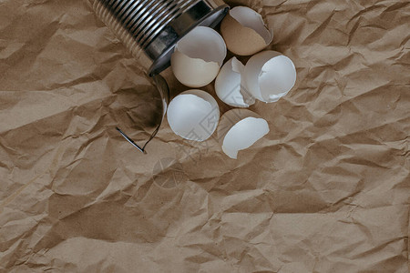 在锡顶视图的蛋壳棕色背景上锡罐中蛋壳的图片