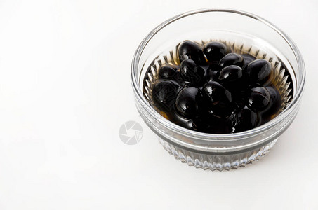 白色背景玻璃碗中煮沸的黑豆背景图片