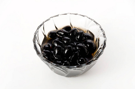 白色背景玻璃碗中煮沸的黑豆背景图片