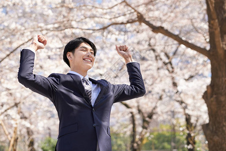 一位日本商人在背景中与樱花合影图片