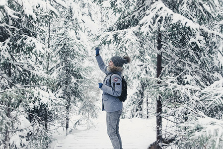 灰色帽子和一件蓝色夹克与白色靴子在美丽的冬季景观的背景上的女孩卡背景图片