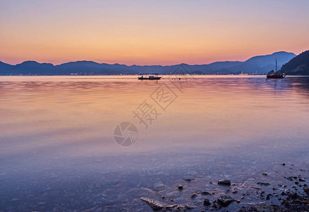 海边的海边晚上山上和小船在海中天空下黄背景图片