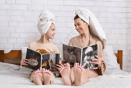 美丽的年轻美女和少女儿阅读时装杂志图片