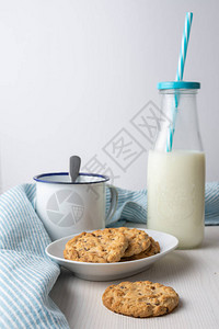 关闭饼干和白板杯子装有稻草和蓝毛衣的牛奶瓶图片