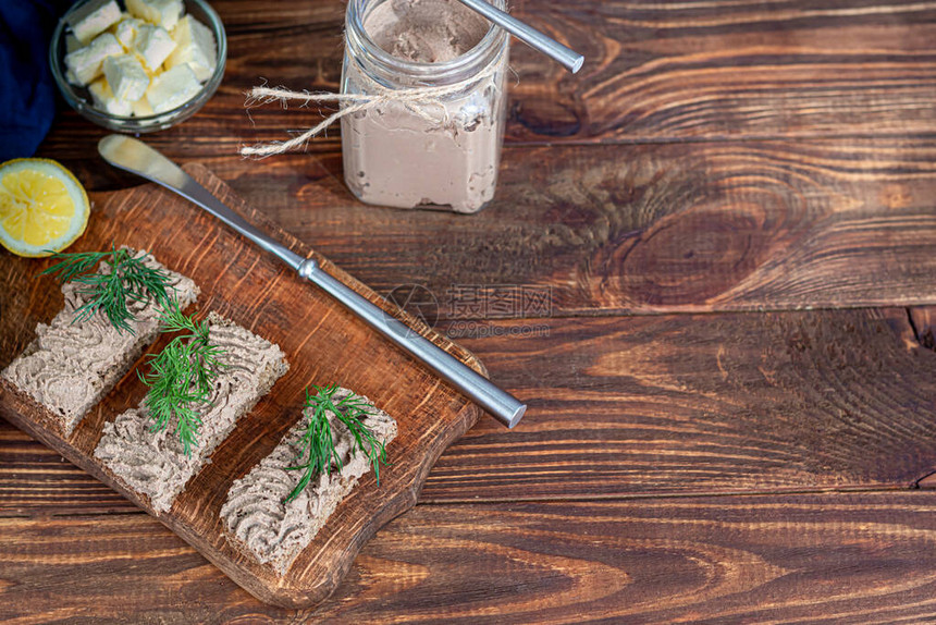 新鲜的自制鸡肝酱配胡萝卜洋葱和黄油饰以莳萝小枝涂在面包上在一个木制的背景图片