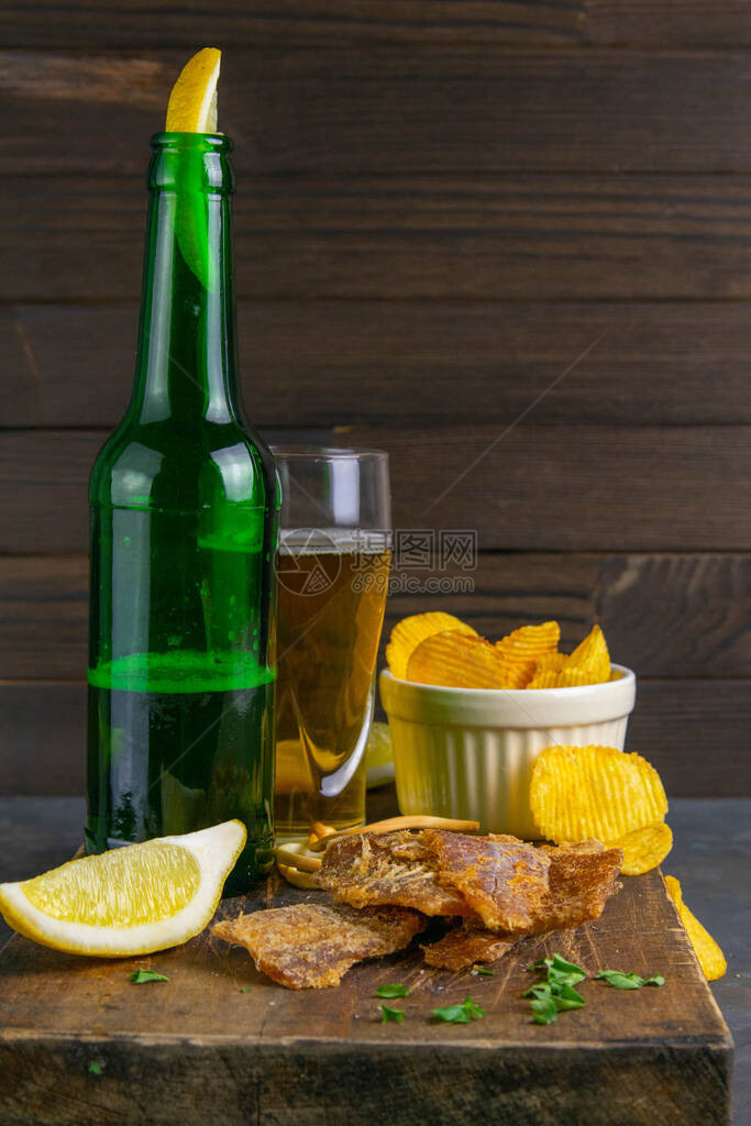 在黑木板上用胡椒和啤酒柠檬和薯片浸泡在图片