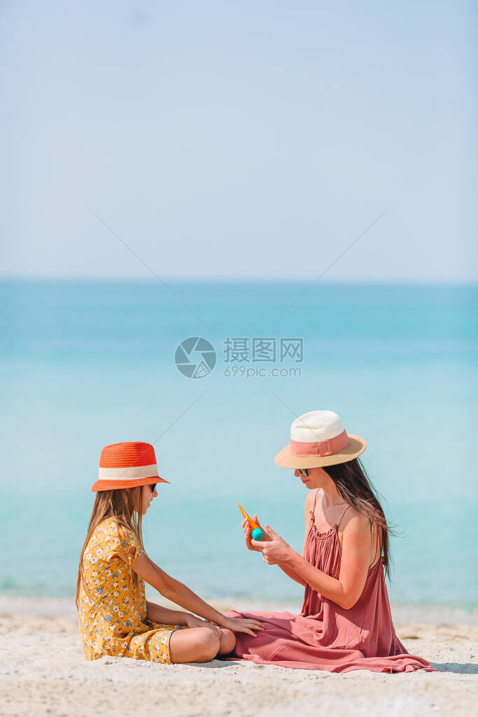 母亲对孩子施晒霜在海滩保护太阳在海图片
