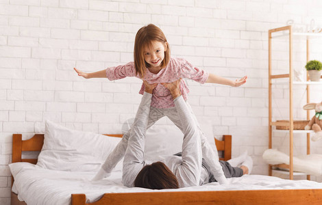 父亲躺在家里的床上抱着小女儿飞图片