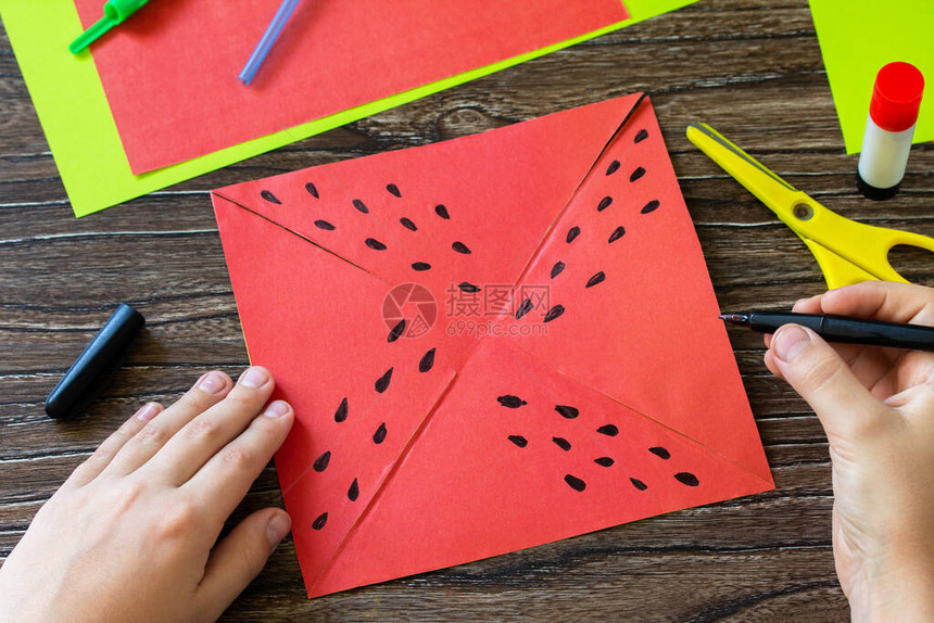 折纸指导步骤7纸风车有趣的玩具西瓜风车在木桌上旋转儿童艺术项目针线活图片