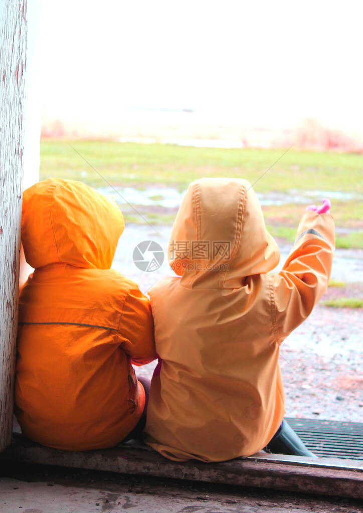 两名在雨中玩耍的年幼儿童穿着雨衣图片