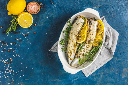 鲭鱼配柠檬百里香迷迭香和料放在白盘上经典蓝色表面上的生腌绿色高清图片素材