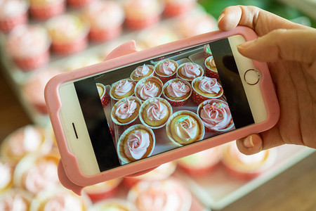 咖啡馆店主使用智能手机拍摄新完成的纸杯蛋糕的照片图片