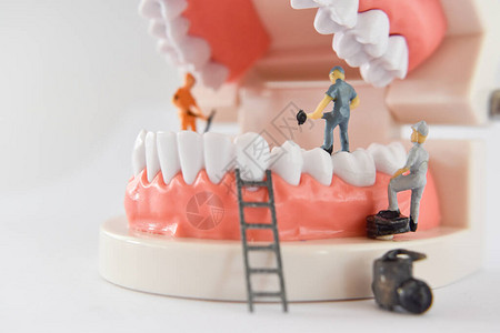 微型人修复牙齿或工人清洁牙齿模型作为医疗和保健清洁牙科护理图片