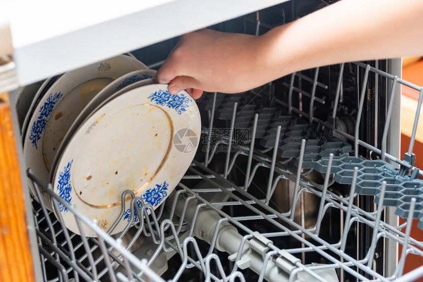 女人把脏盘子放在洗碗机里图片