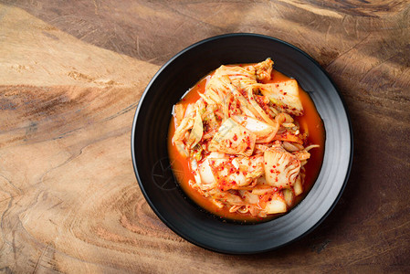 黑盘和木制背景的泡菜卷心菜韩国菜图片