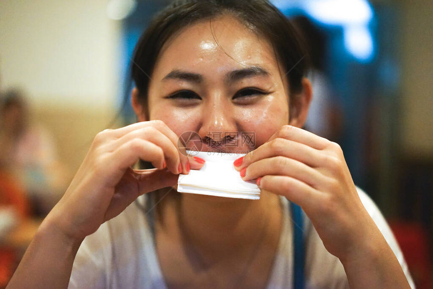 年轻快乐微笑的亚洲女孩在餐厅吃完食物后擦嘴图片