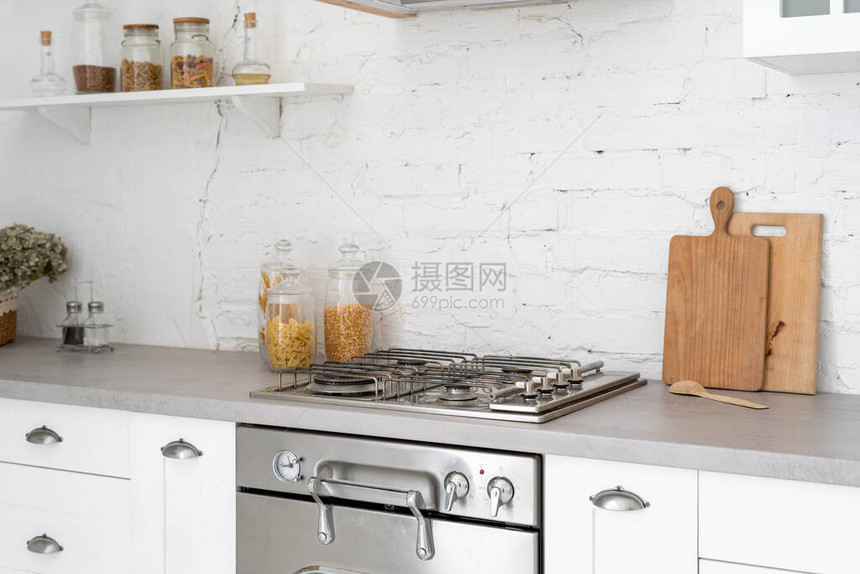 明亮现代风格的厨房内部概念白色家具新燃气灶烤箱木制橱柜和抽屉台面复印空间和墙图片