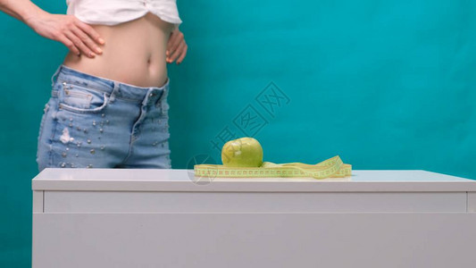 女瘦小的胃部和绿苹果在前景中图片