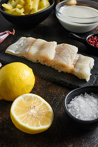 英国传统鱼和薯片配料生鱼片啤酒面糊土豆葱蒜盐胡椒粒在质朴的金属纹理表面图片