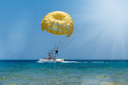 Skydiver驾驶黄降落伞乘快艇在海上飞行背景图片