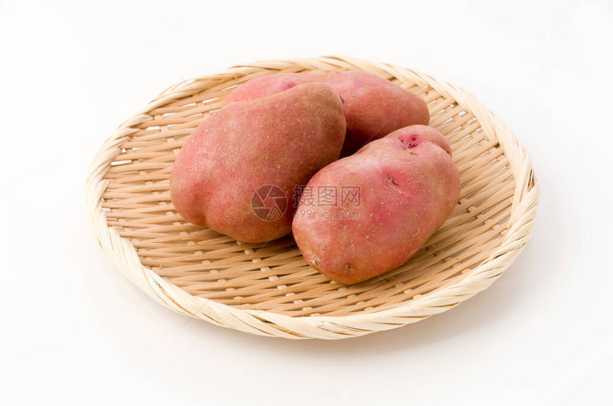 白色背景竹滤锅上的新鲜红皮土豆图片
