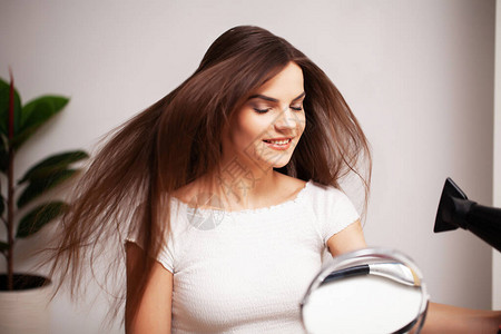 美丽的女人在淋浴后用吹风机吹干头发图片