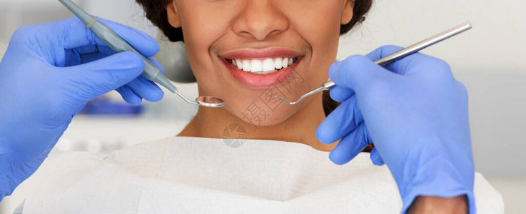 美丽的非洲女微笑和牙医手与牙科工具图片