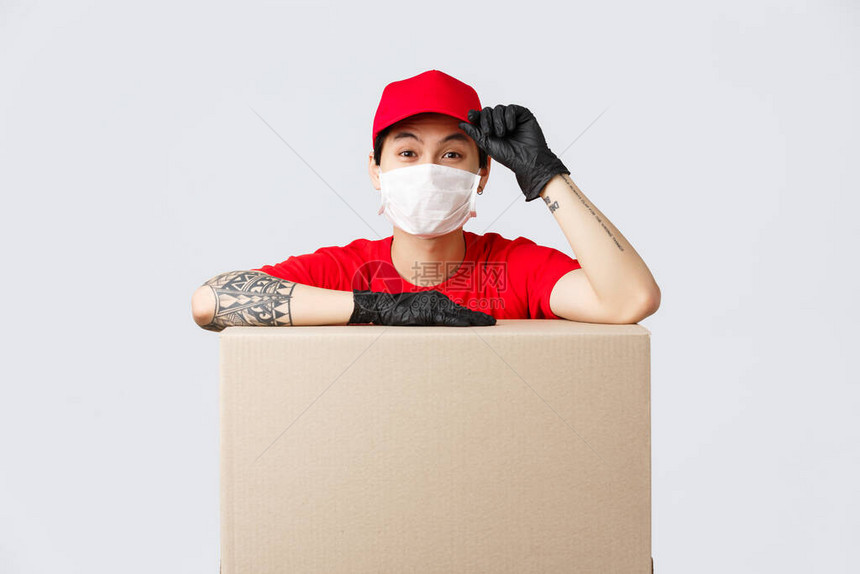 身着红帽和T恤靠在纸板箱或客户包上的信使服务标注为定单向安全自居住区的人转移货物等图片