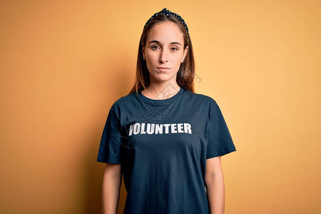 身着义工T恤的年轻美女在黄色背景下从事志愿工作图片